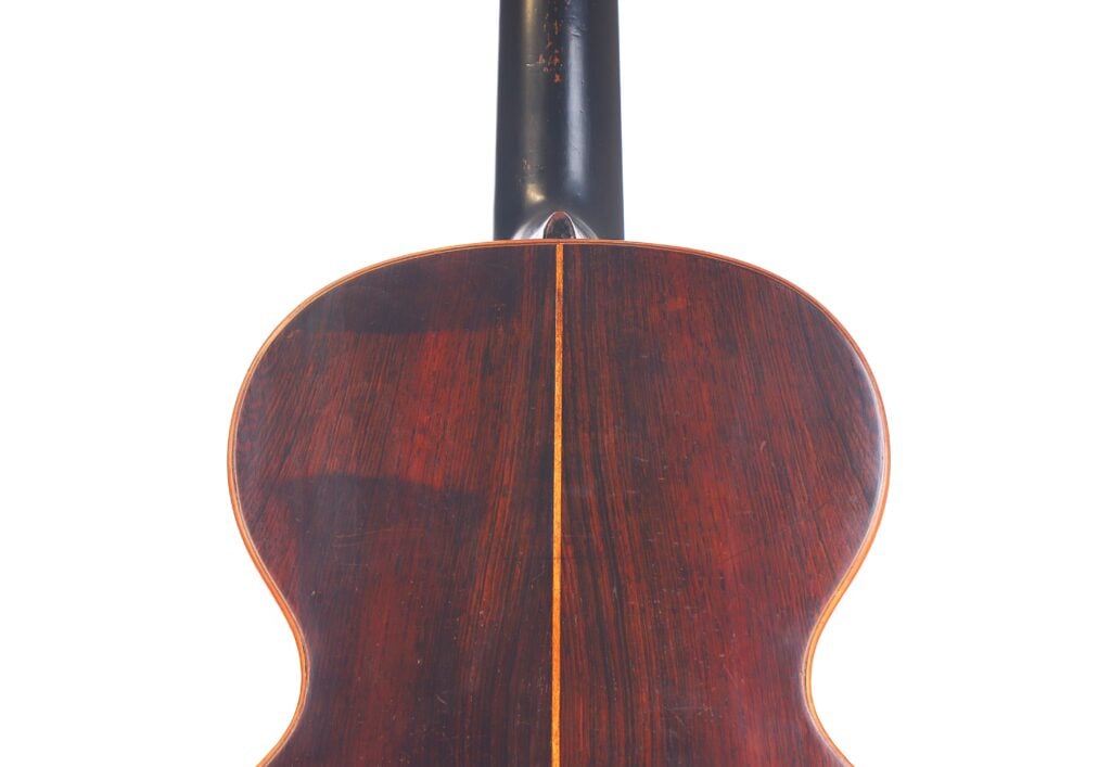 Die Abbildung zeigt den Boden der Markneukirchen 1880 Romantikgitarre, gefertigt aus dunklem, poliertem Holz mit einer Mittelnaht und hellem Randeinband. Oben ist der Hals der Gitarre zu sehen. Die Abbildung zeigt den Boden der Markneukirchen 1880 Romantikgitarre, gefertigt aus dunklem, poliertem Holz mit einer Mittelnaht und hellem Randeinband. Oben ist der Hals der Gitarre zu sehen.