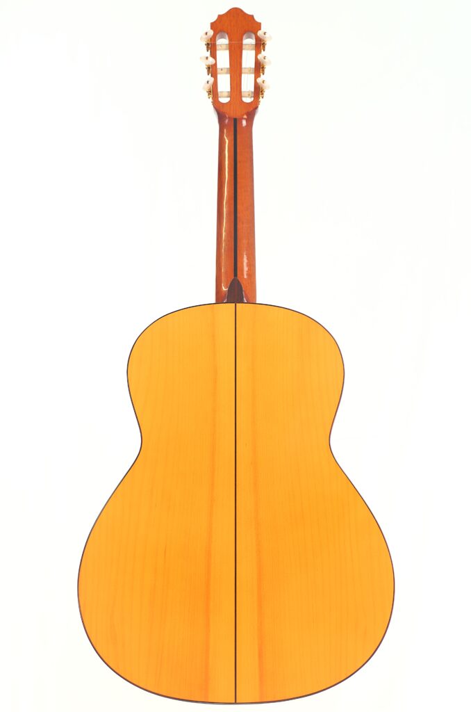 Die Rückansicht der Flamenco-Gitarre „Antonio Bernal 2009“ zeigt ihre helle Holzoberfläche, die dunklen Konturen und den braunen Hals vor einem schlichten weißen Hintergrund. Die Rückansicht der Flamenco-Gitarre „Antonio Bernal 2009“ zeigt ihre helle Holzoberfläche, die dunklen Konturen und den braunen Hals vor einem schlichten weißen Hintergrund.