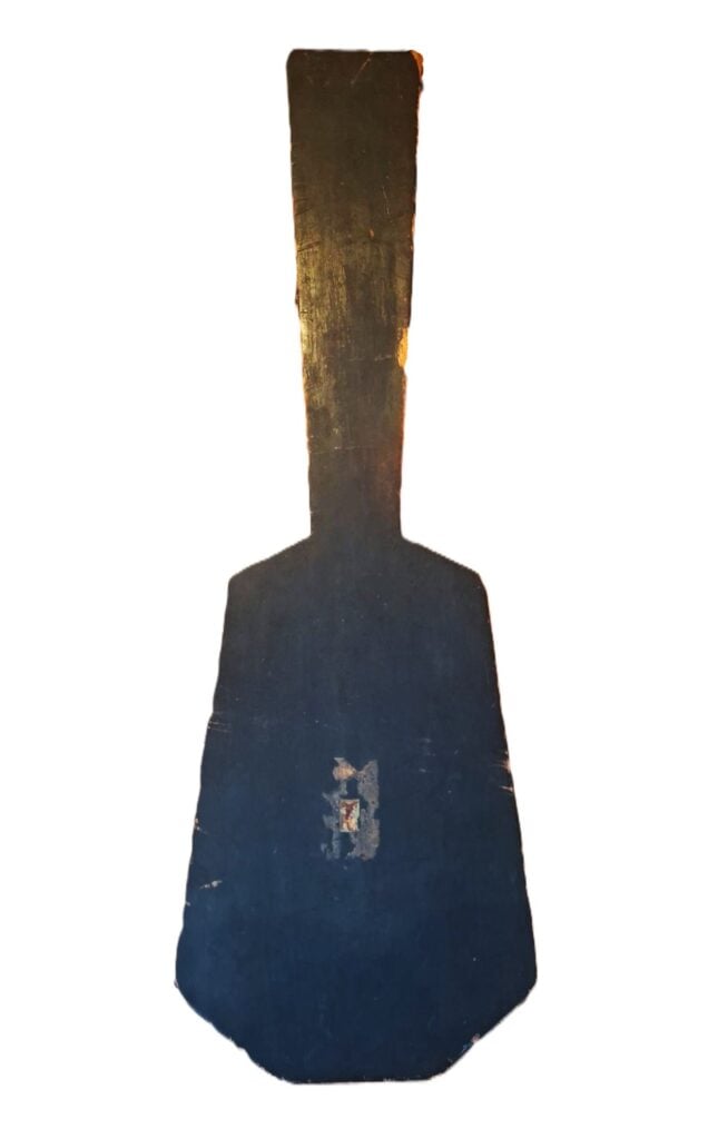 Ein großes, flaches, schwarzes Holzpaddel mit breiter Basis und schmalem Griff, das ähnliche Gebrauchsspuren und handwerkliche Merkmale aufweist wie ein Holzkoffer einer Romantikgitarre um 1820, fotografiert vor weißem Hintergrund. Ein großes, flaches, schwarzes Holzpaddel mit breiter Basis und schmalem Griff, das ähnliche Gebrauchsspuren und handwerkliche Merkmale aufweist wie ein Holzkoffer einer Romantikgitarre um 1820, fotografiert vor weißem Hintergrund.