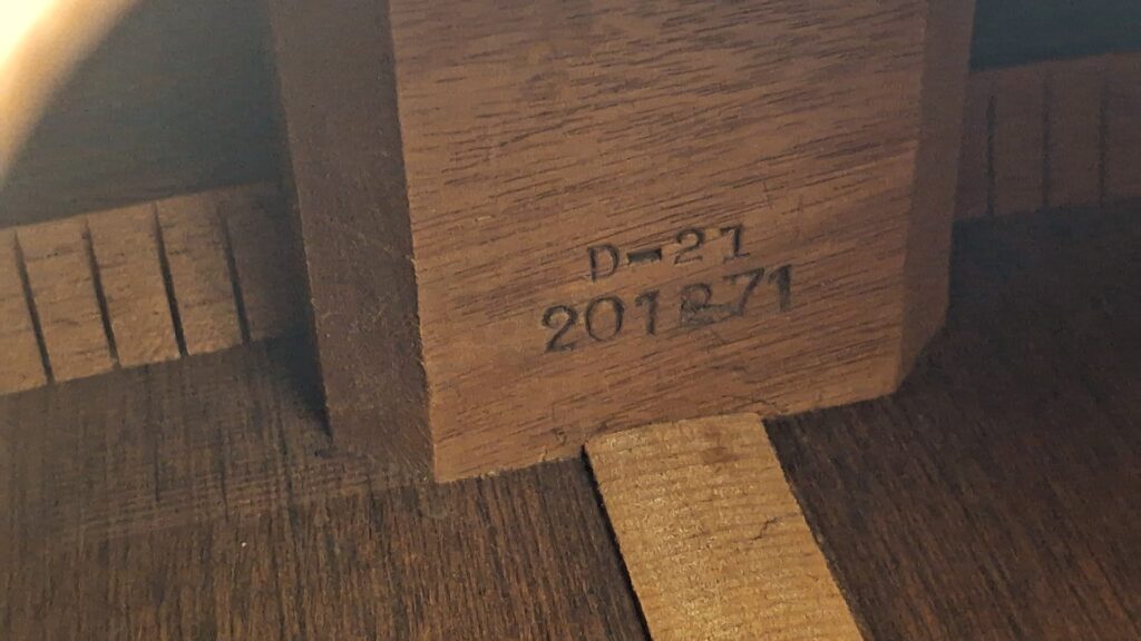 Nahaufnahme des hölzernen Innenraums einer Martin D-21 Akustikgitarre aus dem Jahr 1965, mit dem gestempelten Text "D-21" und "201871" auf dem inneren Holzblock. Nahaufnahme des hölzernen Innenraums einer Martin D-21 Akustikgitarre aus dem Jahr 1965, mit dem gestempelten Text "D-21" und "201871" auf dem inneren Holzblock.