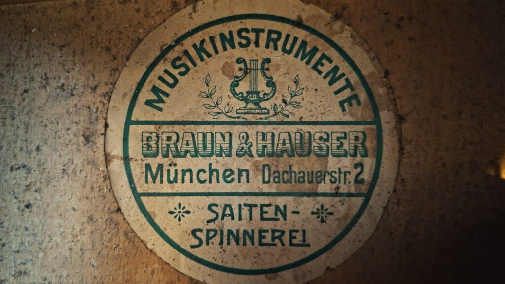 Ein rundes Vintage-Etikett für die Braun & Hauser 1905 Klassische Gitarre zeigt eine Lyra-Grafik und liest: Musikinstrumente Braun & Hauser München Dachauerstr. 2 Saiten-Spinnerei auf einem abgenutzten Hintergrund. Ein rundes Vintage-Etikett für die Braun & Hauser 1905 Klassische Gitarre zeigt eine Lyra-Grafik und liest: Musikinstrumente Braun & Hauser München Dachauerstr. 2 Saiten-Spinnerei auf einem abgenutzten Hintergrund.