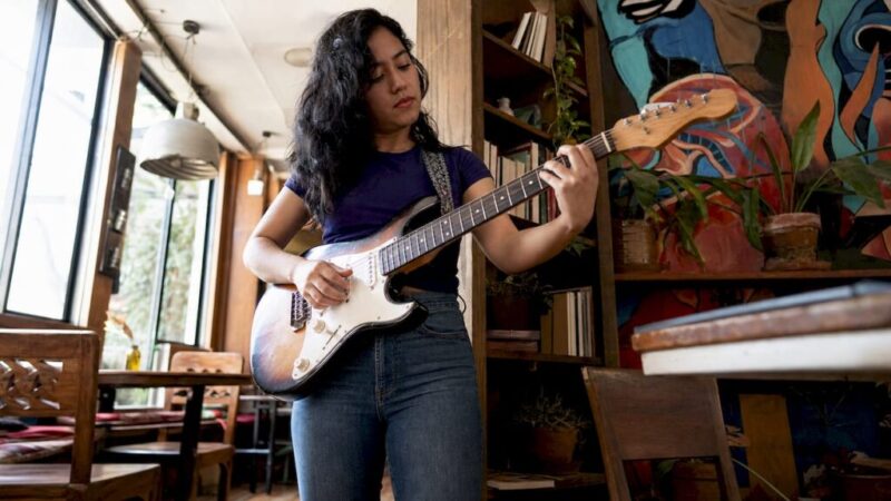 Woman testing guitar playability in studio