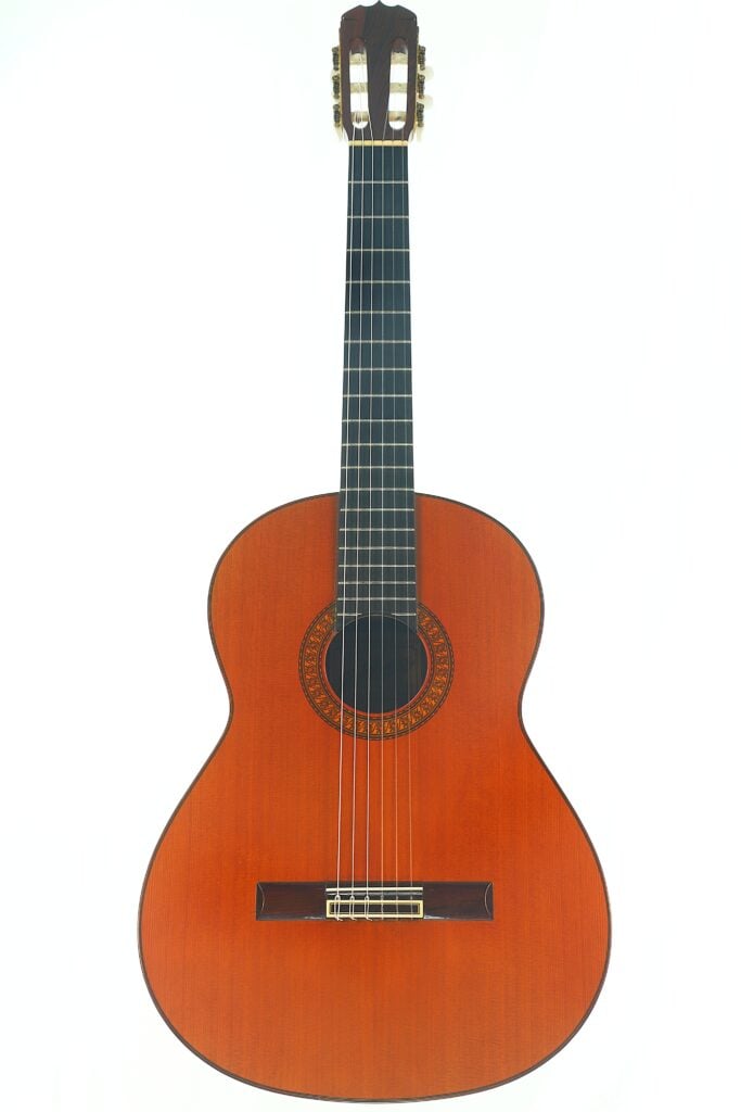 Die José Ramirez 1a 1973 Klassische Gitarre ist eine klassische Akustikgitarre mit sechs Saiten, einem Holzkorpus und einer dekorativen Rosette um das Schallloch, die vor einem weißen Hintergrund abgebildet ist. Die José Ramirez 1a 1973 Klassische Gitarre ist eine klassische Akustikgitarre mit sechs Saiten, einem Holzkorpus und einer dekorativen Rosette um das Schallloch, die vor einem weißen Hintergrund abgebildet ist.