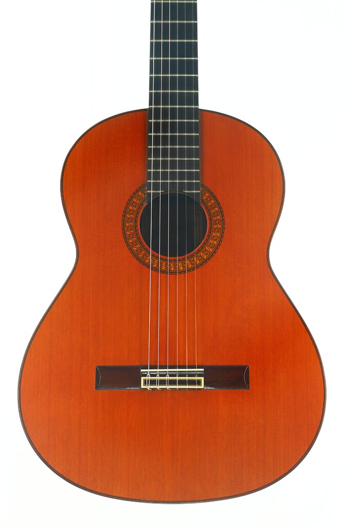 Eine klassische Gitarre von José Ramirez, Baujahr 1973, mit einem Korpus aus Holz, sechs Saiten und einer dekorativen Rosette um das Schallloch, fotografiert vor weißem Hintergrund. Eine klassische Gitarre von José Ramirez, Baujahr 1973, mit einem Korpus aus Holz, sechs Saiten und einer dekorativen Rosette um das Schallloch, fotografiert vor weißem Hintergrund.