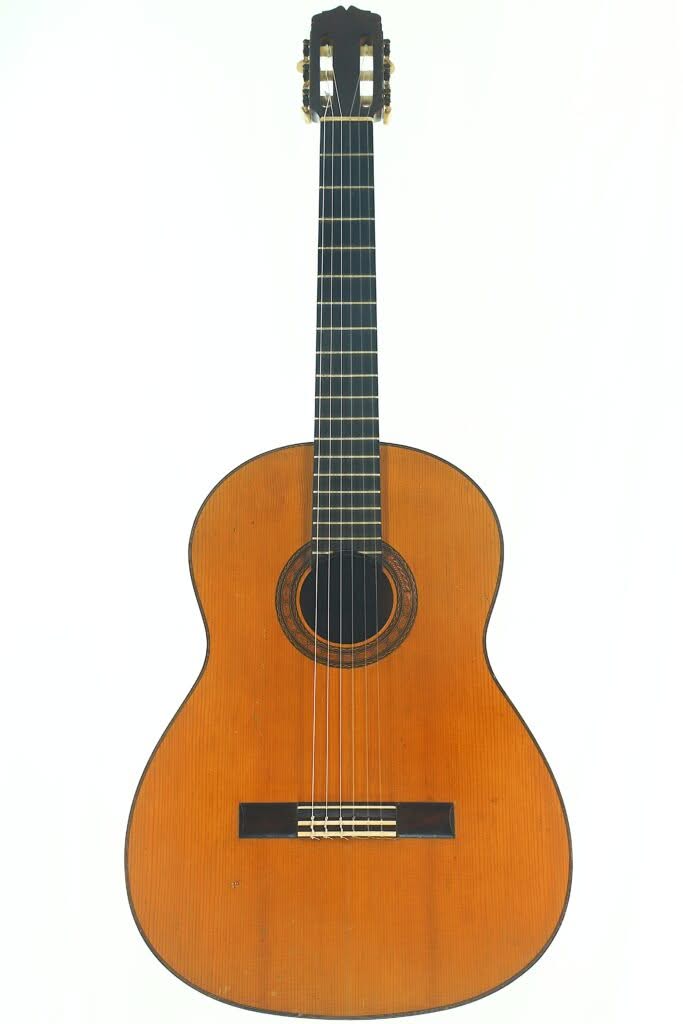 Die Flamenco-Gitarre „Manuel de la Chica 1954“ ist eine klassische Akustikgitarre mit einem Korpus aus Holz, einem dunklen Griffbrett und sechs Saiten, die aufrecht vor einem schlichten weißen Hintergrund abgebildet ist. Die Flamenco-Gitarre „Manuel de la Chica 1954“ ist eine klassische Akustikgitarre mit einem Korpus aus Holz, einem dunklen Griffbrett und sechs Saiten, die aufrecht vor einem schlichten weißen Hintergrund abgebildet ist.