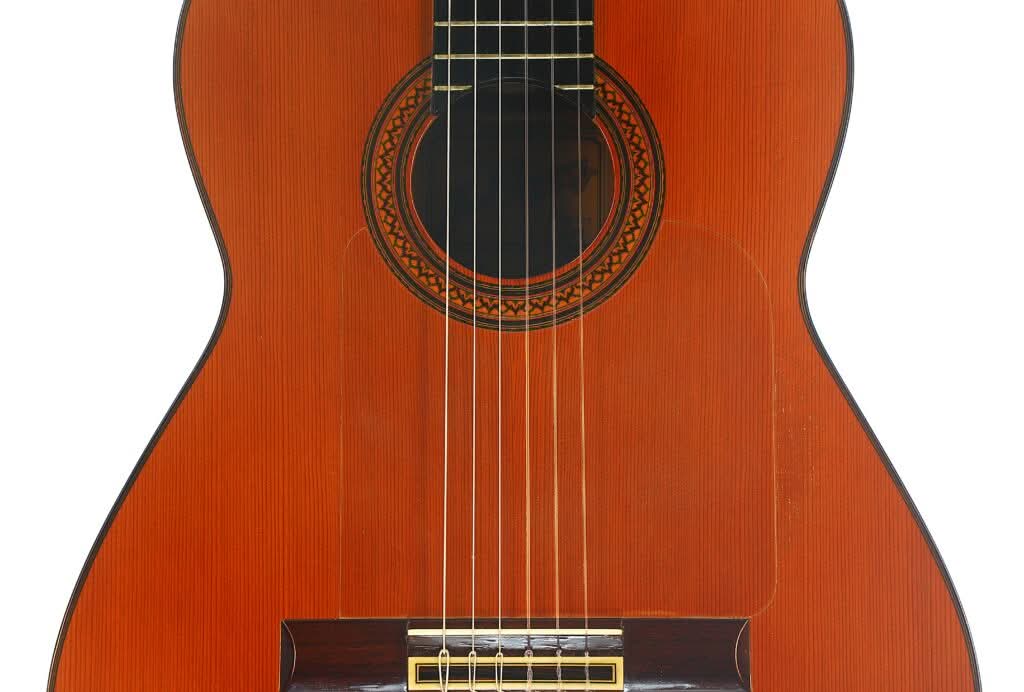 Nahaufnahme des Korpus und der Saiten einer Jose Ramirez 1a Flamenco-Gitarre aus dem Jahr 1968, die das Schallloch, das aufwendig gearbeitete Rosettenmuster und den Holzsteg zeigt. Nahaufnahme des Korpus und der Saiten einer Jose Ramirez 1a Flamenco-Gitarre aus dem Jahr 1968, die das Schallloch, das aufwendig gearbeitete Rosettenmuster und den Holzsteg zeigt.