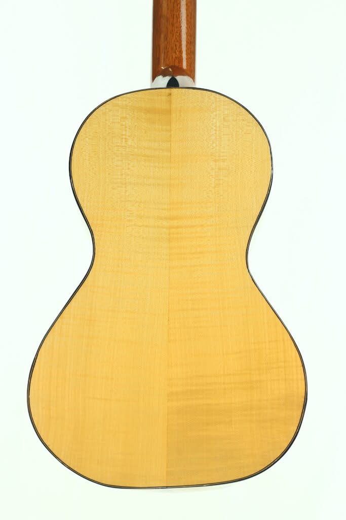 Das Bild zeigt die Rückseite der Lacote Stil Romantikgitarre mit einer hellen Holzoberfläche, dunkler Kantenumrandung und sichtbarer Holzmaserung. Oben ist der Gitarrenhals teilweise zu sehen. Das Bild zeigt die Rückseite der Lacote Stil Romantikgitarre mit einer hellen Holzoberfläche, dunkler Kantenumrandung und sichtbarer Holzmaserung. Oben ist der Gitarrenhals teilweise zu sehen.