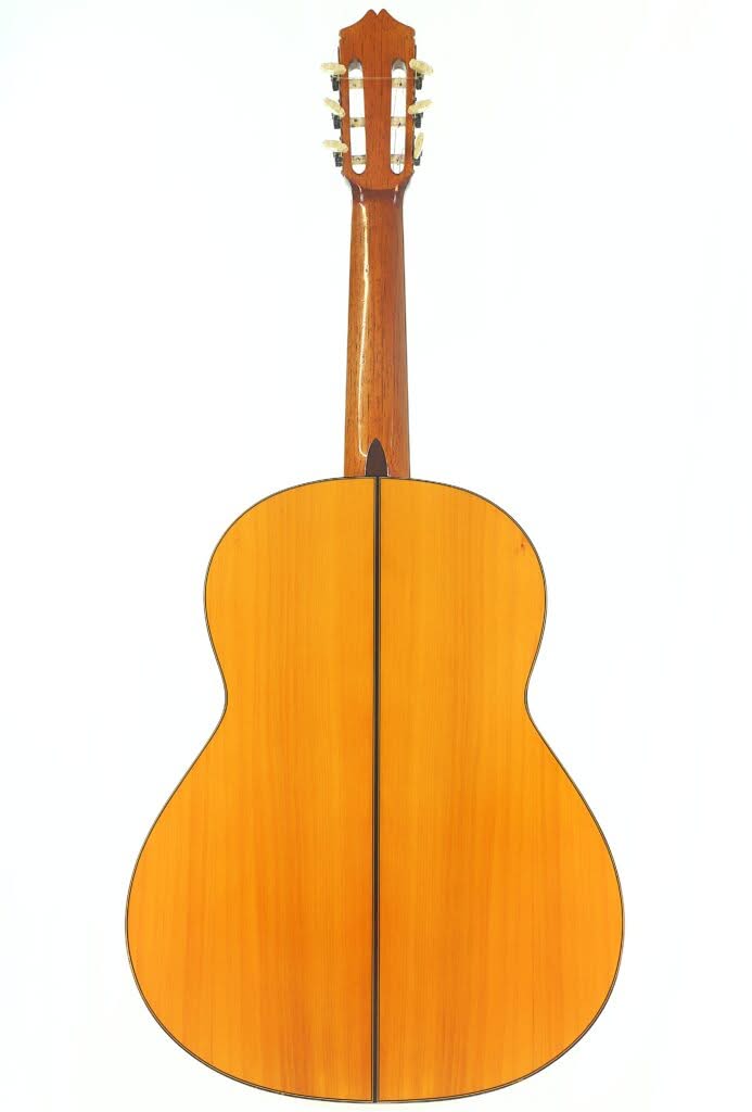 Die Rückansicht einer Flamenco-Gitarre von Sobrinos de Santos Hernandez aus dem Jahr 1974 zeigt den Korpus und den Hals aus Holz mit einer hellbraunen Lackierung und einer vertikalen dunklen Linie in der Mitte. Die Rückansicht einer Flamenco-Gitarre von Sobrinos de Santos Hernandez aus dem Jahr 1974 zeigt den Korpus und den Hals aus Holz mit einer hellbraunen Lackierung und einer vertikalen dunklen Linie in der Mitte.