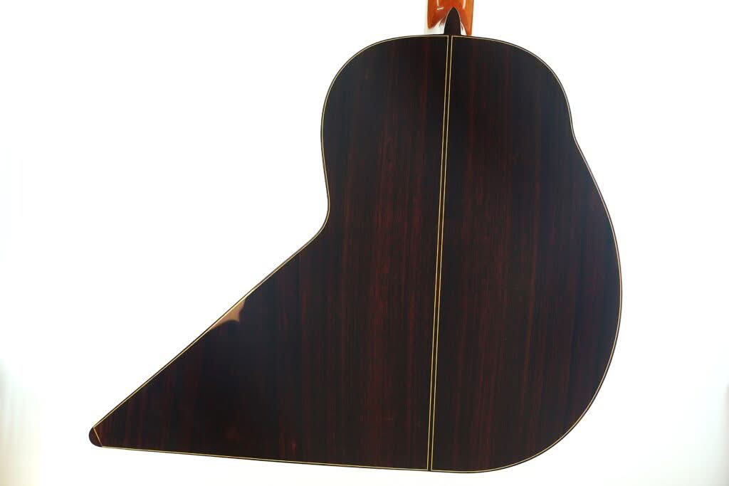Die Rückseite der „Gran Klassische Gitarre“ von Raimundo y Aparicio Corujo mit einer glänzenden, dunklen Holzoberfläche und einer sichtbaren Mittelnaht, fotografiert vor weißem Hintergrund. Die Rückseite der „Gran Klassische Gitarre“ von Raimundo y Aparicio Corujo mit einer glänzenden, dunklen Holzoberfläche und einer sichtbaren Mittelnaht, fotografiert vor weißem Hintergrund.