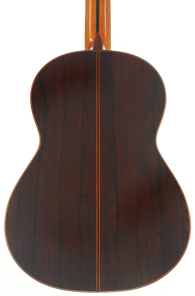 Der Boden der José Ramirez 1a 1973 Klassische Gitarre besteht aus dunklem Holz mit einer Mittellinie und hellen Rändern und weist eine vertikal verlaufende Maserung auf. Der Boden der José Ramirez 1a 1973 Klassische Gitarre besteht aus dunklem Holz mit einer Mittellinie und hellen Rändern und weist eine vertikal verlaufende Maserung auf.
