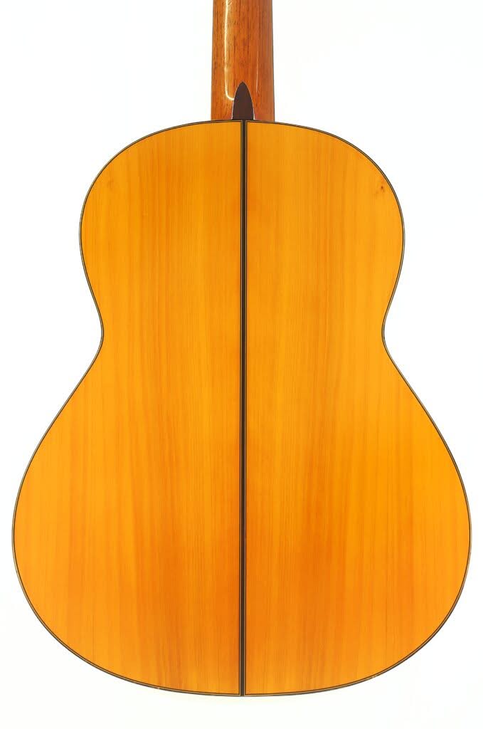 Das Bild zeigt die Rückseite einer Flamenco-Gitarre der Marke „Sobrinos de Santos Hernandez“ aus dem Jahr 1974, bei der poliertes Holz mit einer schwarzen Linie zu sehen ist, die vertikal in der Mitte verläuft, vor einem weißen Hintergrund. Das Bild zeigt die Rückseite einer Flamenco-Gitarre der Marke „Sobrinos de Santos Hernandez“ aus dem Jahr 1974, bei der poliertes Holz mit einer schwarzen Linie zu sehen ist, die vertikal in der Mitte verläuft, vor einem weißen Hintergrund.