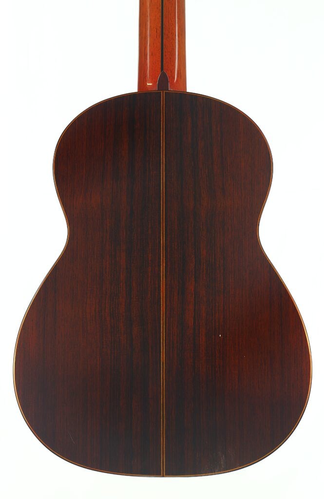 Rückansicht der 7-saitigen klassischen Gitarre „Melchor Rodriguez 1980 Ramirez Stil“ mit dunkler Holzoberfläche, einer Mittellinie und dezenten Maserungsmustern. Rückansicht der 7-saitigen klassischen Gitarre „Melchor Rodriguez 1980 Ramirez Stil“ mit dunkler Holzoberfläche, einer Mittellinie und dezenten Maserungsmustern.