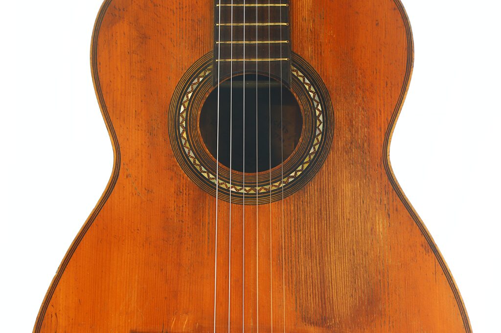 Nahaufnahme des Korpus einer „Ricardo Sanchis Nacher 1940 Augustin Barrios Klassische Gitarre“ mit Holzfinish, wobei das Schallloch, die Rosette und die Saiten vor einem weißen Hintergrund besonders hervorgehoben werden. Nahaufnahme des Korpus einer „Ricardo Sanchis Nacher 1940 Augustin Barrios Klassische Gitarre“ mit Holzfinish, wobei das Schallloch, die Rosette und die Saiten vor einem weißen Hintergrund besonders hervorgehoben werden.