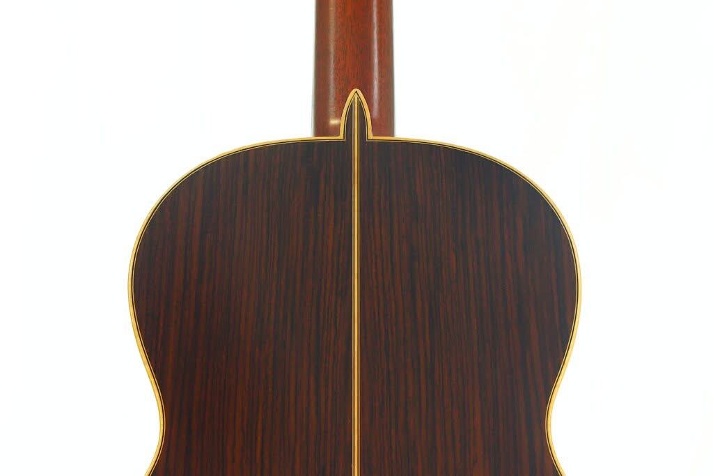 Nahaufnahme der Rückseite einer „Hauser Klassische“-Gitarre von Alastair McNeil aus dem Jahr 1997, die sich durch dunkles Holz mit einem helleren Mittelstreifen und gelber Einfassung auszeichnet, vor weißem Hintergrund. Nahaufnahme der Rückseite einer „Hauser Klassische“-Gitarre von Alastair McNeil aus dem Jahr 1997, die sich durch dunkles Holz mit einem helleren Mittelstreifen und gelber Einfassung auszeichnet, vor weißem Hintergrund.