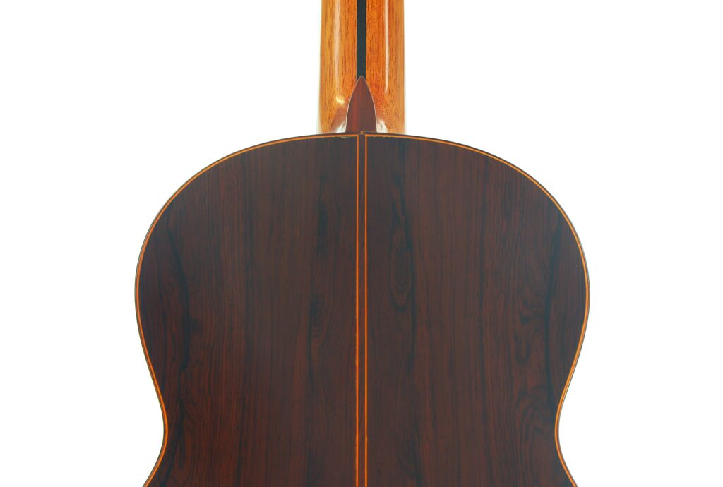 Nahaufnahme der Rückseite einer José Ramirez 1a 1973 Klassische Gitarre, die eine dunkle Holzmaserung mit einer Mittelnaht und einer hellen Einfassung entlang der Kanten und des Rückens zeigt. Nahaufnahme der Rückseite einer José Ramirez 1a 1973 Klassische Gitarre, die eine dunkle Holzmaserung mit einer Mittelnaht und einer hellen Einfassung entlang der Kanten und des Rückens zeigt.
