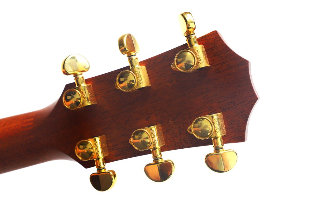 Nahaufnahme der Rückseite des Kopfes einer Taylor 712 Akustikgitarre mit sechs goldenen Stimmwirbeln an einem Holzhals, fotografiert vor weißem Hintergrund. Nahaufnahme der Rückseite des Kopfes einer Taylor 712 Akustikgitarre mit sechs goldenen Stimmwirbeln an einem Holzhals, fotografiert vor weißem Hintergrund.