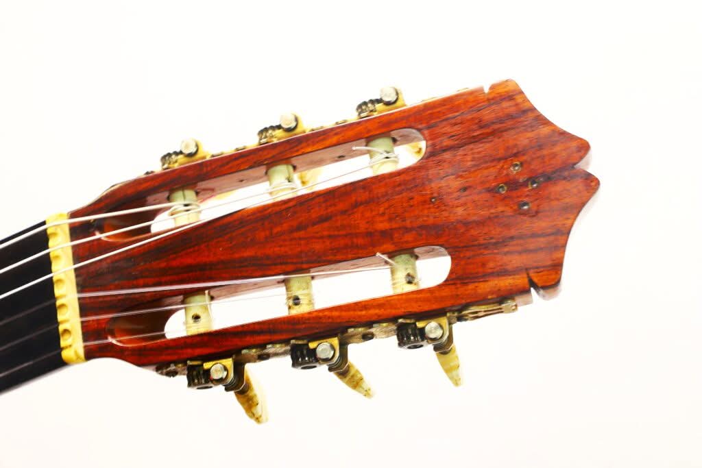 Nahaufnahme des Kopfes einer Flamenco-Gitarre von Sobrinos de Santos Hernandez aus dem Jahr 1974, mit Stimmwirbeln aus Holz und elfenbeinfarbenen Stimmknöpfen vor weißem Hintergrund. Nahaufnahme des Kopfes einer Flamenco-Gitarre von Sobrinos de Santos Hernandez aus dem Jahr 1974, mit Stimmwirbeln aus Holz und elfenbeinfarbenen Stimmknöpfen vor weißem Hintergrund.