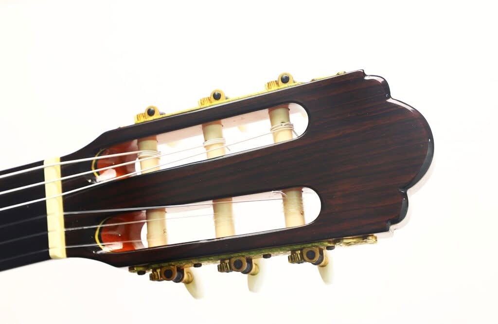 Nahaufnahme des Kopfes der „Gran Klassische Gitarre“ von Raimundo y Aparicio Corujo mit Nylonsaiten und goldenen Stimmwirbeln vor weißem Hintergrund. Nahaufnahme des Kopfes der „Gran Klassische Gitarre“ von Raimundo y Aparicio Corujo mit Nylonsaiten und goldenen Stimmwirbeln vor weißem Hintergrund.