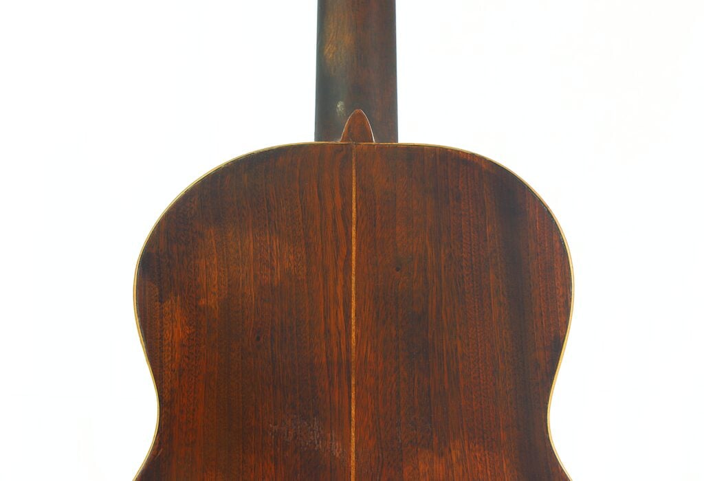 Rückansicht der „José Ramirez 1932 Klassische Gitarre“ mit einer dunklen, polierten Holzoberfläche, die die Maserung und die Mittelnaht des Holzes hervorhebt, vor einem weißen Hintergrund. Rückansicht der „José Ramirez 1932 Klassische Gitarre“ mit einer dunklen, polierten Holzoberfläche, die die Maserung und die Mittelnaht des Holzes hervorhebt, vor einem weißen Hintergrund.