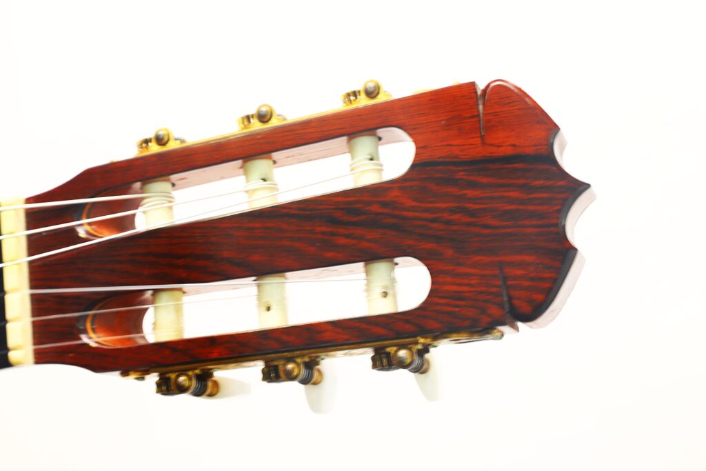 Nahaufnahme des Kopfes einer José Ramirez 1a 1973 Klassische Gitarre mit Holzoberfläche, weißen Stimmwirbeln und Nylonsaiten vor weißem Hintergrund. Nahaufnahme des Kopfes einer José Ramirez 1a 1973 Klassische Gitarre mit Holzoberfläche, weißen Stimmwirbeln und Nylonsaiten vor weißem Hintergrund.