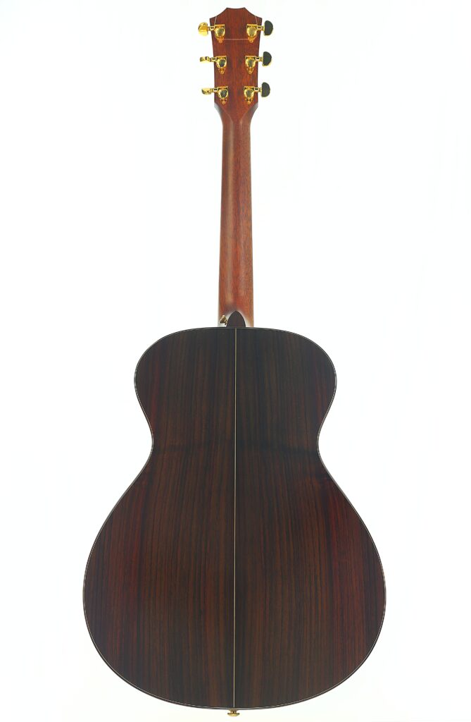 Die Rückseite der Taylor 712 Akustikgitarre besticht durch eine satte, dunkle Holzoberfläche mit goldenen Stimmwirbeln und einer markanten Mittelnaht, die vertikal über den Korpus verläuft. Die Rückseite der Taylor 712 Akustikgitarre besticht durch eine satte, dunkle Holzoberfläche mit goldenen Stimmwirbeln und einer markanten Mittelnaht, die vertikal über den Korpus verläuft.