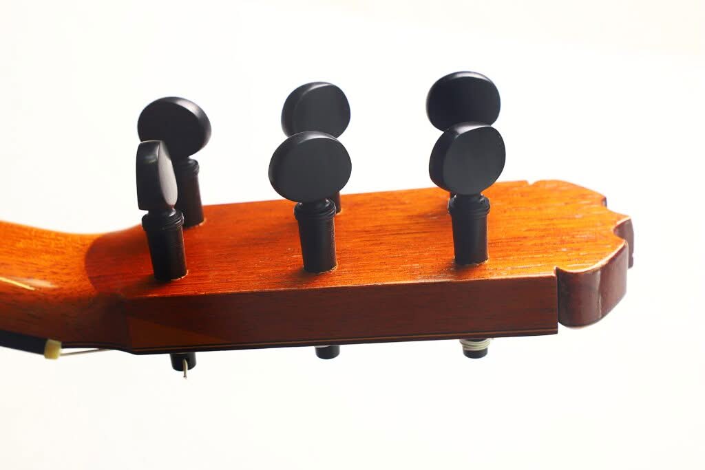 Nahaufnahme des Kopfes einer Jose Ramirez 1a Flamenco-Gitarre aus dem Jahr 1968, auf der vier schwarze Stimmwirbel vor weißem Hintergrund zu sehen sind. Nahaufnahme des Kopfes einer Jose Ramirez 1a Flamenco-Gitarre aus dem Jahr 1968, auf der vier schwarze Stimmwirbel vor weißem Hintergrund zu sehen sind.
