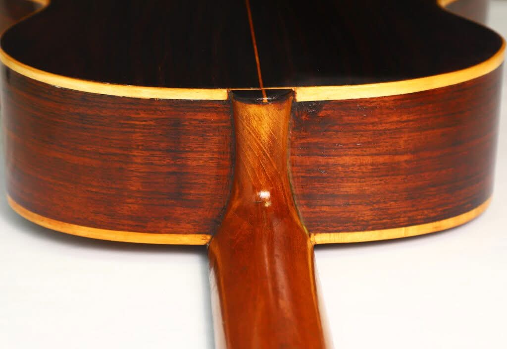 Nahaufnahme des Hals-Korpus-Übergangs der „Salvador Ibanez 1900 Klassische Gitarre“, die die polierte Holzmaserung, die sorgfältige Verarbeitung und die hellen Einfassungen hervorhebt. Nahaufnahme des Hals-Korpus-Übergangs der „Salvador Ibanez 1900 Klassische Gitarre“, die die polierte Holzmaserung, die sorgfältige Verarbeitung und die hellen Einfassungen hervorhebt.