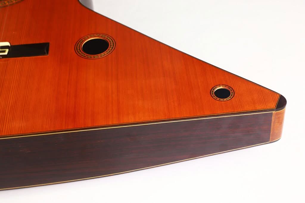 Eine Nahaufnahme des Holzkörpers der „Gran Klassische Gitarre“ von Raimundo y Aparicio Corujo, die ihre eleganten Rundungen, Schalllöcher und die polierte Oberfläche vor einem weißen Hintergrund hervorhebt. Eine Nahaufnahme des Holzkörpers der „Gran Klassische Gitarre“ von Raimundo y Aparicio Corujo, die ihre eleganten Rundungen, Schalllöcher und die polierte Oberfläche vor einem weißen Hintergrund hervorhebt.