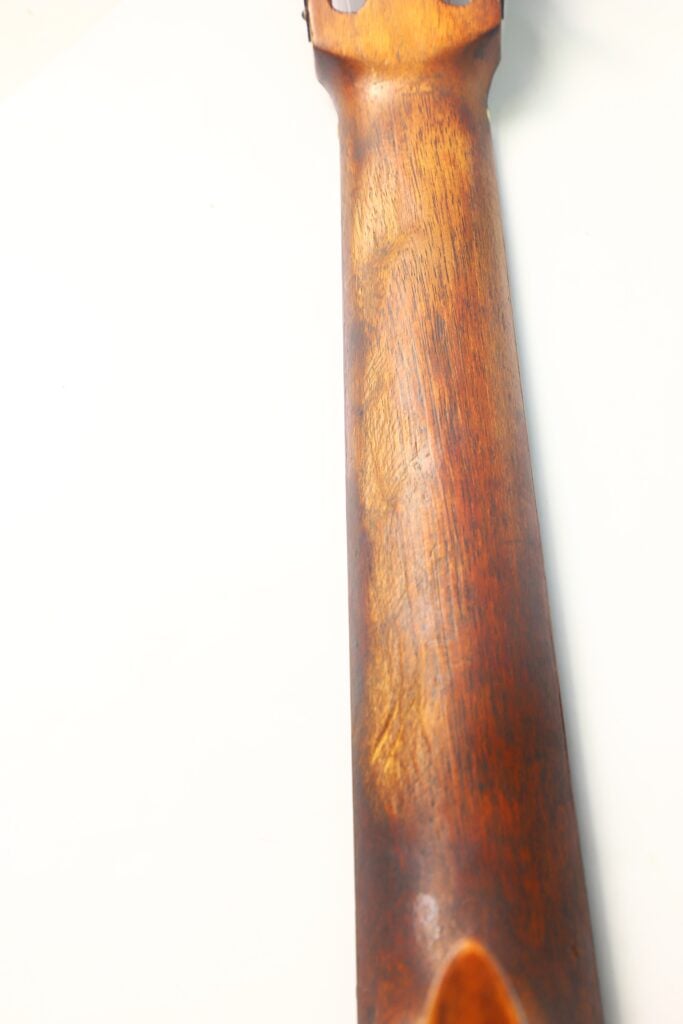 Eine Nahaufnahme des abgenutzten Halses einer José-Ramirez-Klassikgitarre aus dem Jahr 1932 hebt deren glatte Oberfläche und natürliche Holzmaserung vor weißem Hintergrund hervor. Eine Nahaufnahme des abgenutzten Halses einer José-Ramirez-Klassikgitarre aus dem Jahr 1932 hebt deren glatte Oberfläche und natürliche Holzmaserung vor weißem Hintergrund hervor.