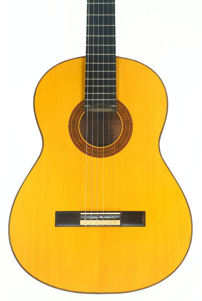 Eine Nahaufnahme der Jose de Jesus 2024 Blanca Modell Reyes Flamenco-Gitarre mit einem hellen Holzkorpus, einer filigranen Rosette um das Schallloch und sechs Saiten, fotografiert vor weißem Hintergrund. Eine Nahaufnahme der Jose de Jesus 2024 Blanca Modell Reyes Flamenco-Gitarre mit einem hellen Holzkorpus, einer filigranen Rosette um das Schallloch und sechs Saiten, fotografiert vor weißem Hintergrund.