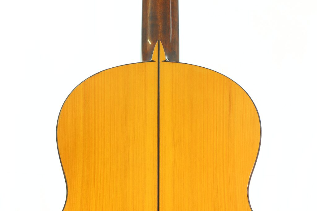 Nahaufnahme der Rückseite einer Jose de Jesus 2024 Blanca Modell Reyes Flamenco-Gitarre mit heller Holzmaserung, einer dunklen Mittelnaht und dunklen Kanten, wobei sich der Hals vor einem schlichten weißen Hintergrund nach oben erstreckt. Nahaufnahme der Rückseite einer Jose de Jesus 2024 Blanca Modell Reyes Flamenco-Gitarre mit heller Holzmaserung, einer dunklen Mittelnaht und dunklen Kanten, wobei sich der Hals vor einem schlichten weißen Hintergrund nach oben erstreckt.