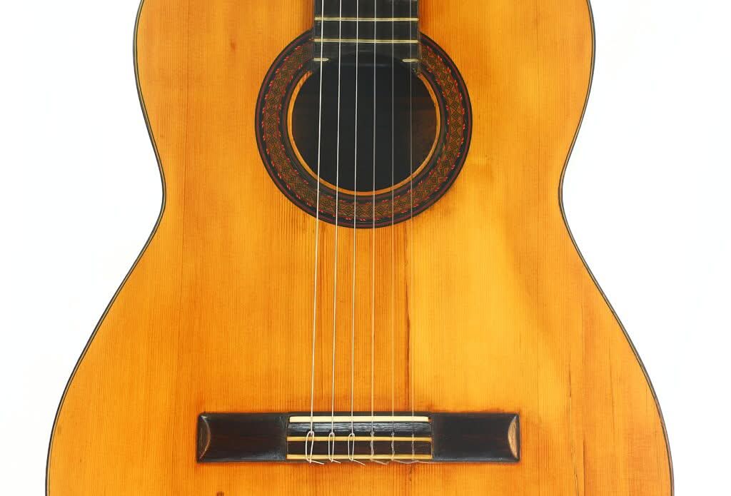 Nahaufnahme des Korpus einer klassischen Akustikgitarre von Modesto Borreguero aus dem Jahr 1955, mit Schallloch, Saiten und Holzsteg vor weißem Hintergrund. Nahaufnahme des Korpus einer klassischen Akustikgitarre von Modesto Borreguero aus dem Jahr 1955, mit Schallloch, Saiten und Holzsteg vor weißem Hintergrund.