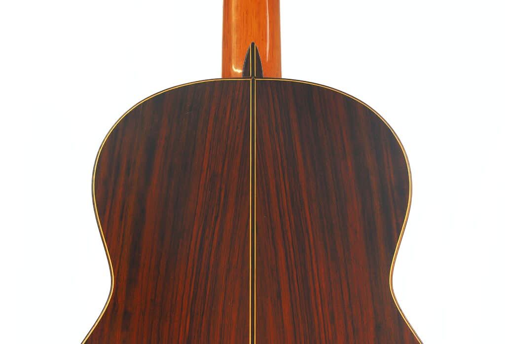 Die Rückseite der „Klassische Gitarre“ von Antonio Duran aus dem Jahr 1974, gefertigt aus dunklem Holz mit einem gelben Mittelstreifen, vor weißem Hintergrund. Die Rückseite der „Klassische Gitarre“ von Antonio Duran aus dem Jahr 1974, gefertigt aus dunklem Holz mit einem gelben Mittelstreifen, vor weißem Hintergrund.