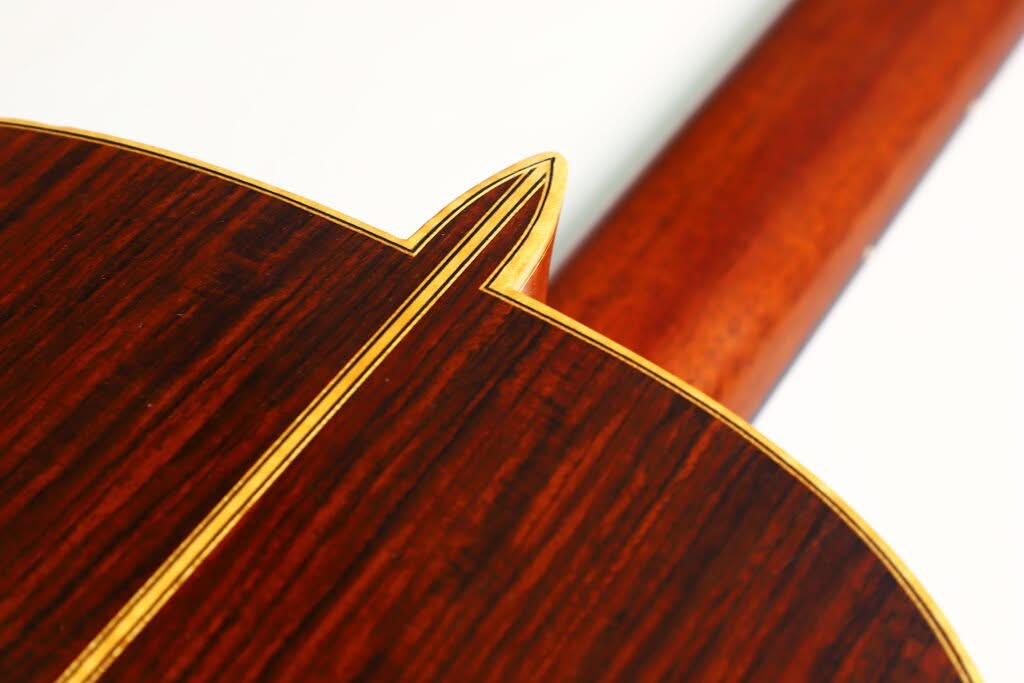 Nahaufnahme des Holzrückens und des Halses der „Alastair McNeil 1997 Hauser Klassische Gitarre“, die die detailreiche Handwerkskunst mit einer zentralen gelben Einlage und einer satten, dunklen Holzmaserung hervorhebt. Nahaufnahme des Holzrückens und des Halses der „Alastair McNeil 1997 Hauser Klassische Gitarre“, die die detailreiche Handwerkskunst mit einer zentralen gelben Einlage und einer satten, dunklen Holzmaserung hervorhebt.