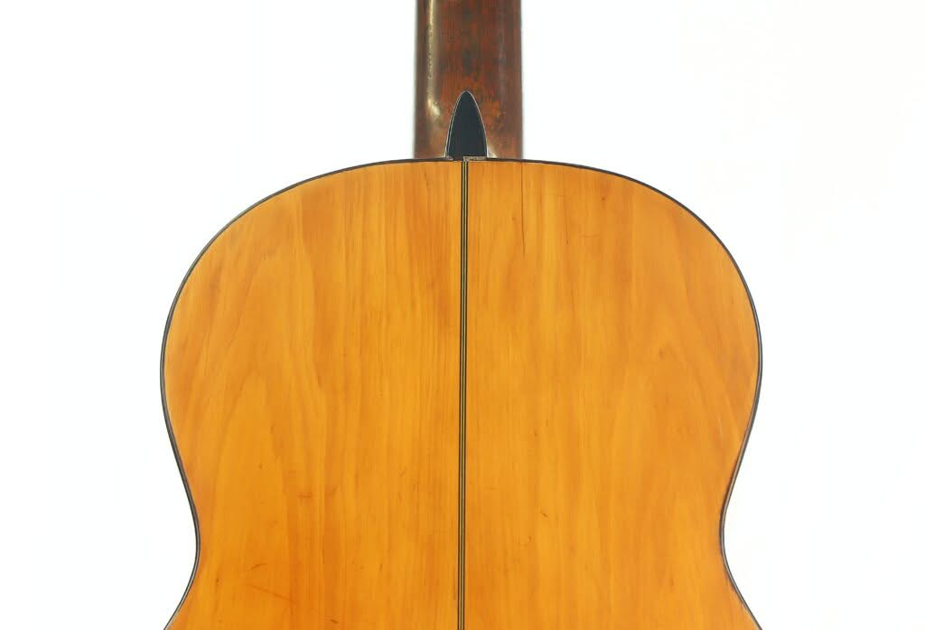 Der Boden der Akustikgitarre „Modesto Borreguero 1955“, gefertigt aus hellbraunem Holz mit glänzender Oberfläche, sichtbarer Mittelnaht und schwarzer Einfassung, ist vor einem weißen Hintergrund abgebildet. Der Boden der Akustikgitarre „Modesto Borreguero 1955“, gefertigt aus hellbraunem Holz mit glänzender Oberfläche, sichtbarer Mittelnaht und schwarzer Einfassung, ist vor einem weißen Hintergrund abgebildet.
