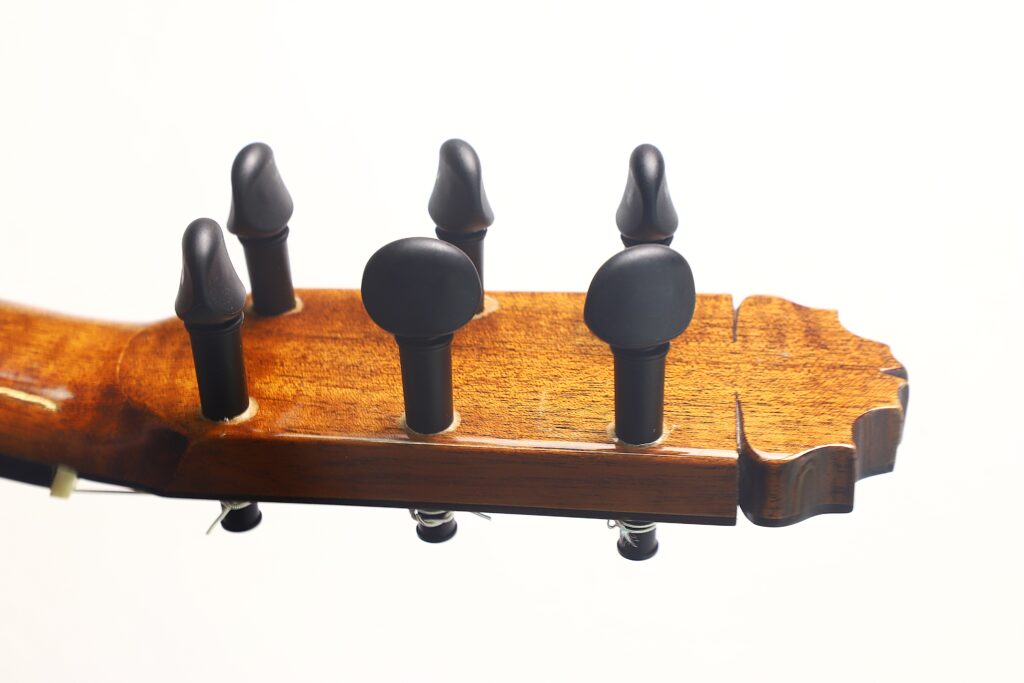 Nahaufnahme der Rückseite des Kopfes einer Jose de Jesus 2024 Blanca Modell Reyes Flamenco-Gitarre, auf der fünf schwarze Stimmwirbel vor weißem Hintergrund zu sehen sind. Nahaufnahme der Rückseite des Kopfes einer Jose de Jesus 2024 Blanca Modell Reyes Flamenco-Gitarre, auf der fünf schwarze Stimmwirbel vor weißem Hintergrund zu sehen sind.