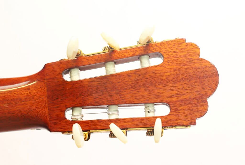 Nahaufnahme des Kopfstücks einer „Chet Atkins Klassische Gitarre“ von Juan Estruch aus dem Jahr 1971, mit weißen Stimmwirbeln und Nylonsaiten vor einem schlichten weißen Hintergrund. Nahaufnahme des Kopfstücks einer „Chet Atkins Klassische Gitarre“ von Juan Estruch aus dem Jahr 1971, mit weißen Stimmwirbeln und Nylonsaiten vor einem schlichten weißen Hintergrund.