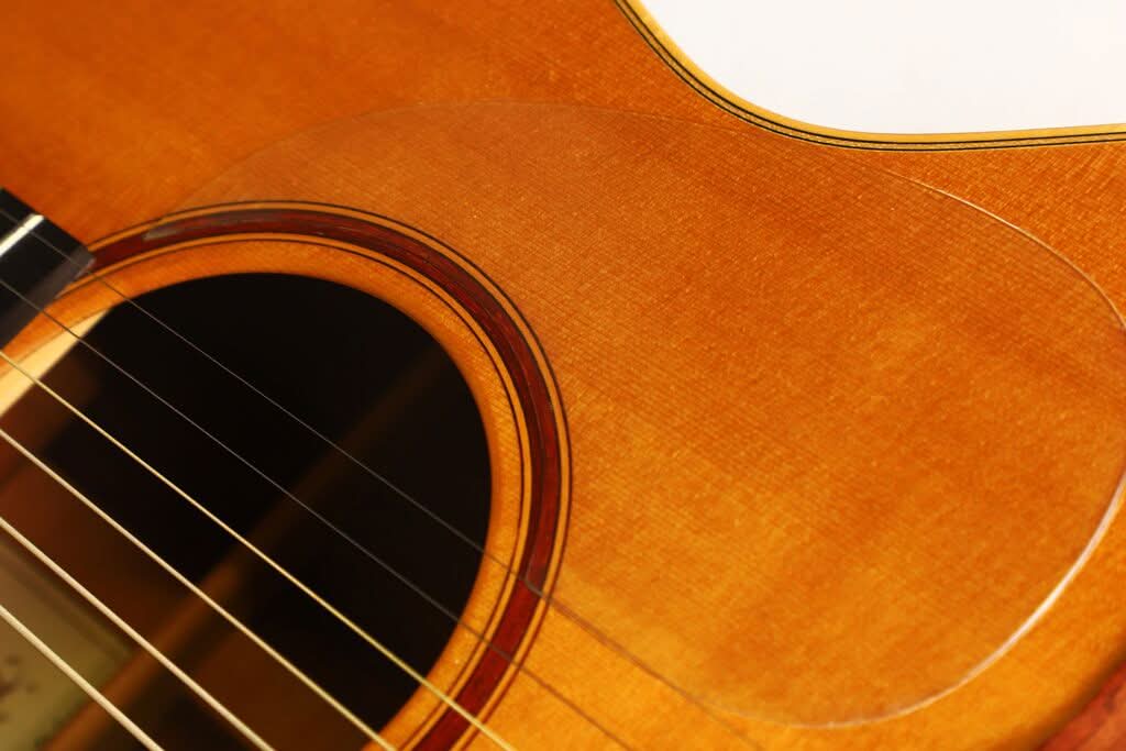 Nahaufnahme des Korpus der Lakewood M-54 Akustikgitarre aus dem Jahr 1998, bei der das Schallloch, die Saiten und die warme, braune Holzmaserung besonders gut zur Geltung kommen. Nahaufnahme des Korpus der Lakewood M-54 Akustikgitarre aus dem Jahr 1998, bei der das Schallloch, die Saiten und die warme, braune Holzmaserung besonders gut zur Geltung kommen.