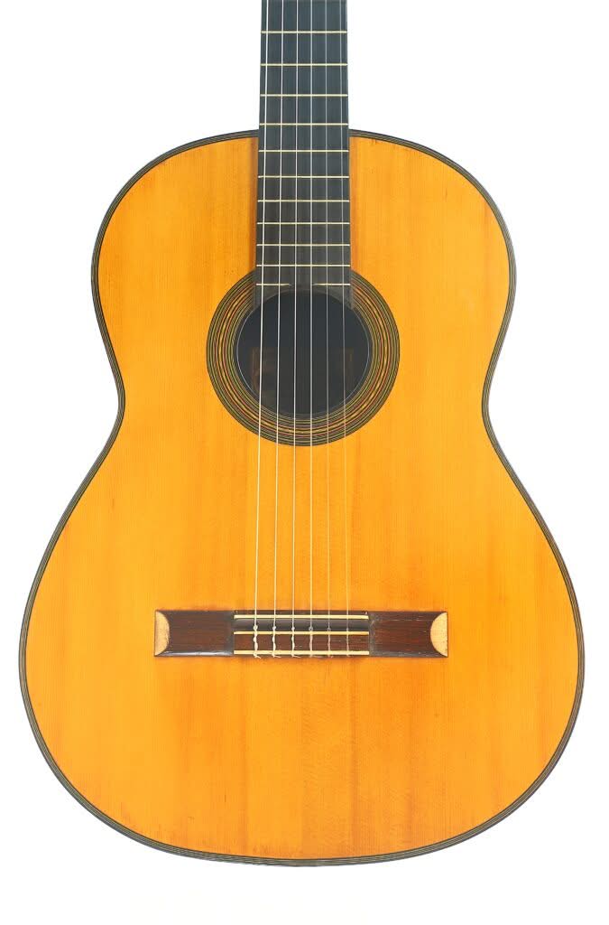 Die „Francisco Simplicio 1931 Torres Klassische Gitarre“ ist eine klassische Akustikgitarre mit naturbelassener Holzoberfläche, sechs Saiten, rundem Schallloch und dunklem Steg, die vor einem weißen Hintergrund abgebildet ist. Die „Francisco Simplicio 1931 Torres Klassische Gitarre“ ist eine klassische Akustikgitarre mit naturbelassener Holzoberfläche, sechs Saiten, rundem Schallloch und dunklem Steg, die vor einem weißen Hintergrund abgebildet ist.