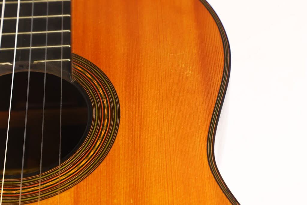 Nahaufnahme der „Francisco Simplicio 1931 Torres Klassische Gitarre“ mit ihrem Schallloch, den Saiten und dem warmbraunen Holzkorpus vor weißem Hintergrund. Nahaufnahme der „Francisco Simplicio 1931 Torres Klassische Gitarre“ mit ihrem Schallloch, den Saiten und dem warmbraunen Holzkorpus vor weißem Hintergrund.