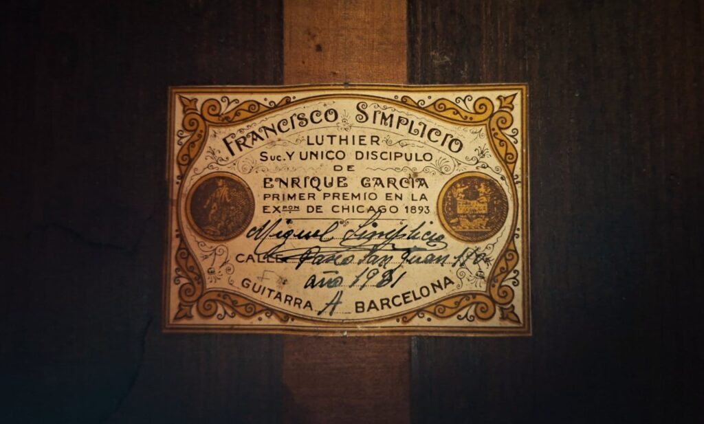 Auf einem Etikett im Inneren der „Francisco Simplicio 1931 Torres Klassische Gitarre“ steht: „Francisco Simplicio, Gitarrenbauer, einziger Schüler von Enrique Garcia, Erster Preis bei der Ausstellung in Chicago 1893, Barcelona“, ergänzt durch handschriftliche Notizen und verzierte Rahmen. Auf einem Etikett im Inneren der „Francisco Simplicio 1931 Torres Klassische Gitarre“ steht: „Francisco Simplicio, Gitarrenbauer, einziger Schüler von Enrique Garcia, Erster Preis bei der Ausstellung in Chicago 1893, Barcelona“, ergänzt durch handschriftliche Notizen und verzierte Rahmen.