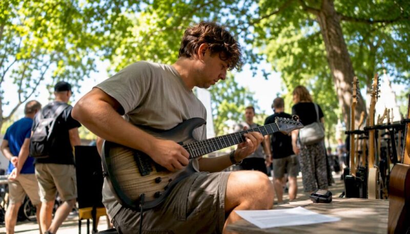 Ein junger Mann testet eine Gitarre im Musikgeschäft und lässt sich dabei von den verschiedenen Klängen inspirieren.