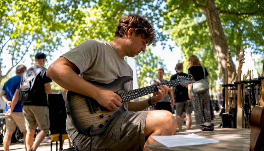 Ein junger Mann testet eine Gitarre im Musikgeschäft und lässt sich dabei von den verschiedenen Klängen inspirieren.