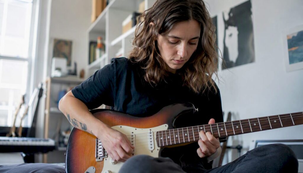 Hände, die mit kraftvollem Anschlag Gitarre spielen