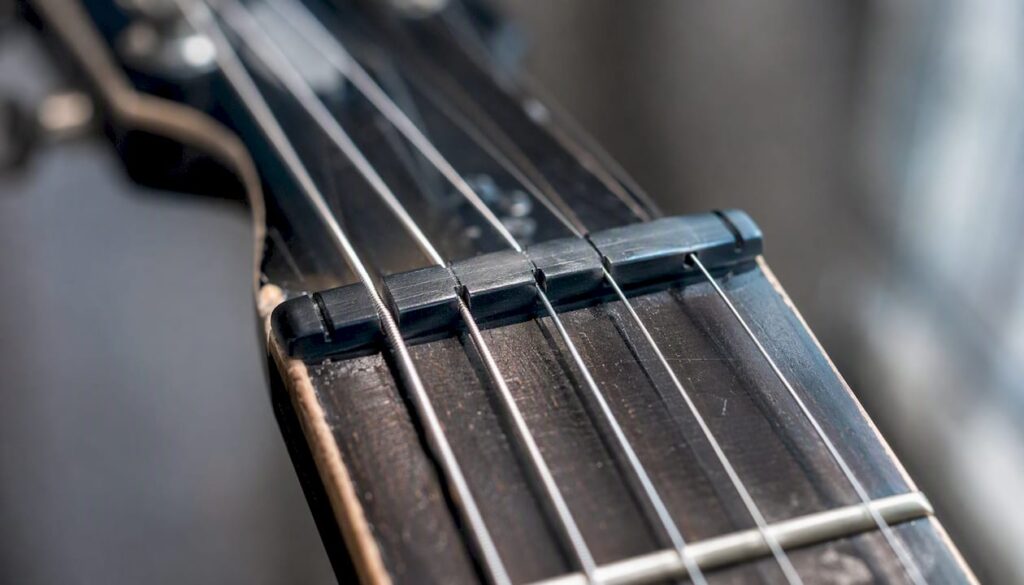 Detailaufnahme: Der schwarze Graphitsattel auf dem Hals einer Gitarre