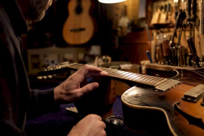 Appraisal hand touching vintage guitar fretboard