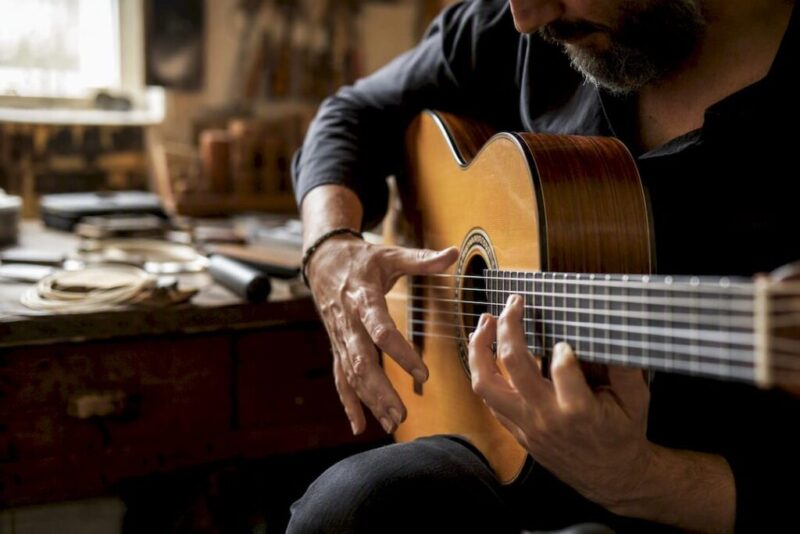 Hände zupfen die Saiten einer Flamenco-Gitarre
