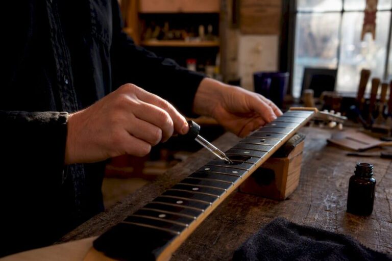 Hands cleaning ebony fretboard close-up