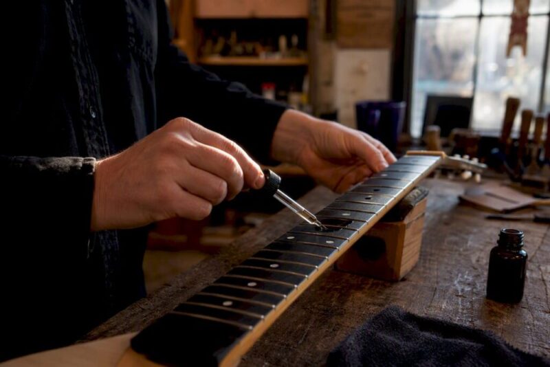 Hands cleaning ebony fretboard close-up