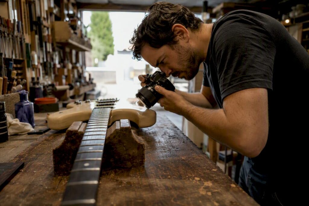 Technician photographing guitar fretboard damage